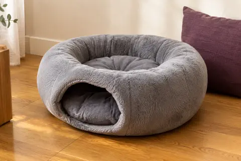 Lit grotte gris pour chat en peluche, avec entrée semi-fermée et coussin intérieur amovible.