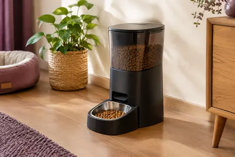 Distributeur automatique de croquettes noir avec sa gamelle en acier inoxydable dans un intérieur chaleureux