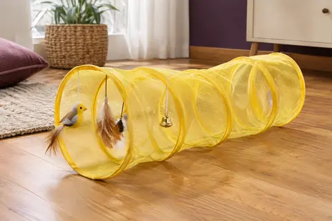 Tunnel spirale jaune pour chat en nylon, avec oiseau, plumes et clochette, posé dans un intérieur chaleureux.