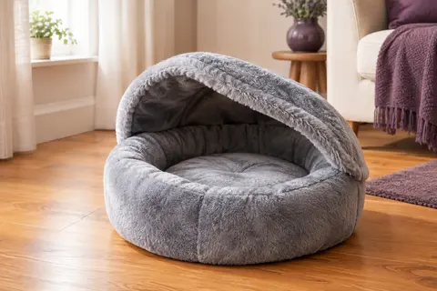 Lit grotte rond gris pour chat avec toit souple en peluche, posé dans un intérieur chaleureux.